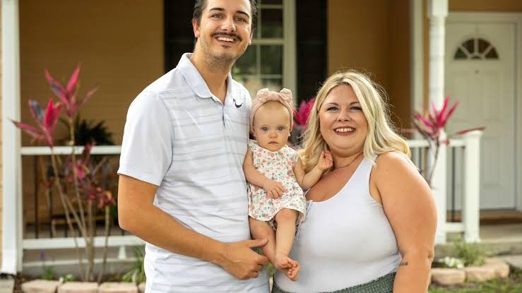 A couple standing together with their young child